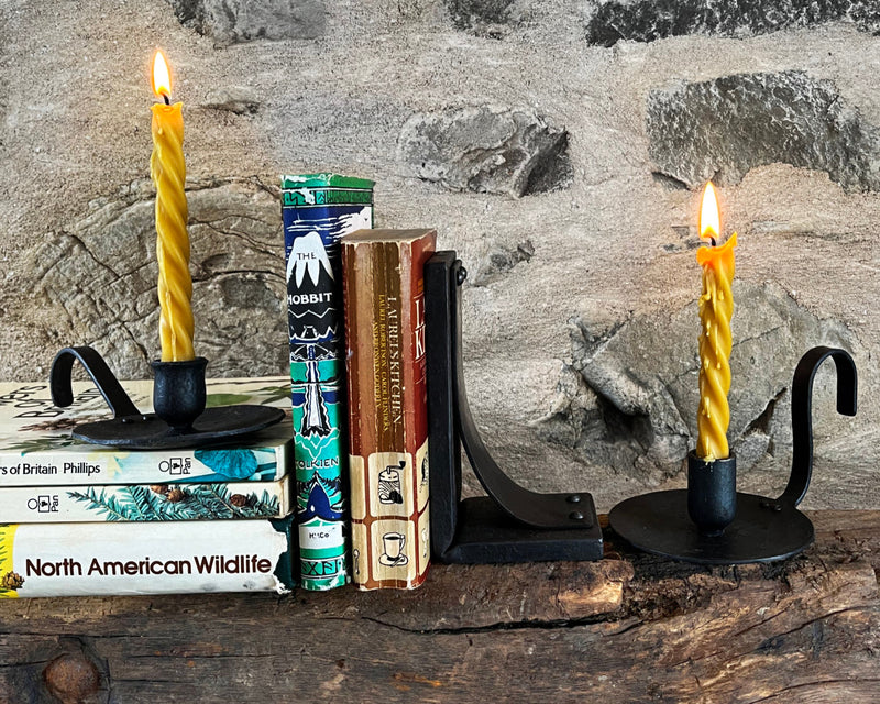 Decorative handmade bookends with forged candles on a stone fireplace background