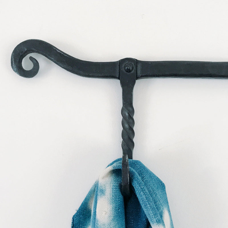Decorative black metal hook with a blue towel on a white background