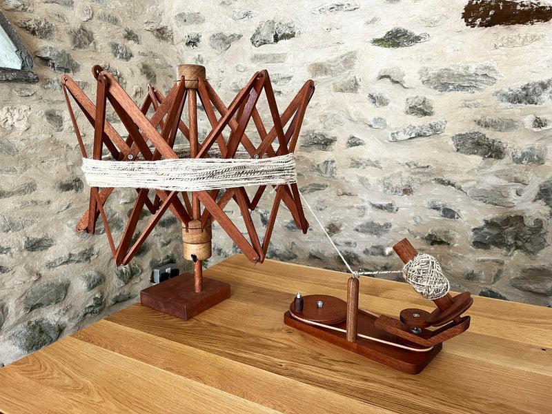 Wooden yarn swift and winder on a wooden surface with a stone wall background